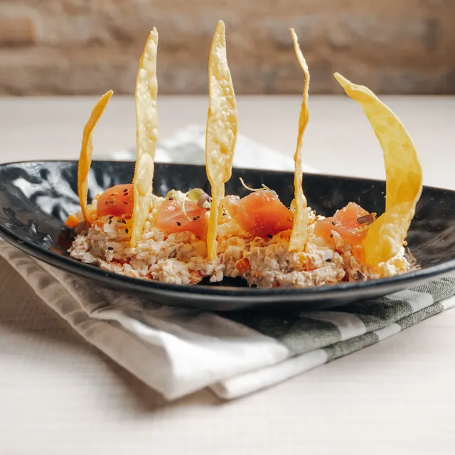 Rice Russian salad with bluefin tuna sashimi and crispy corn, on a long black plate