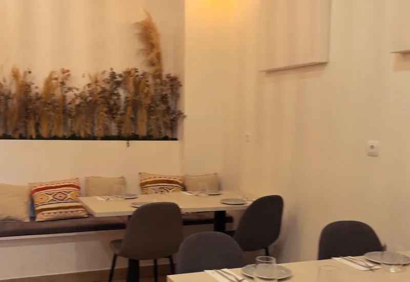 Mesas puestas junto al banco corrido del salón, con cojines y espigas secas en la pared