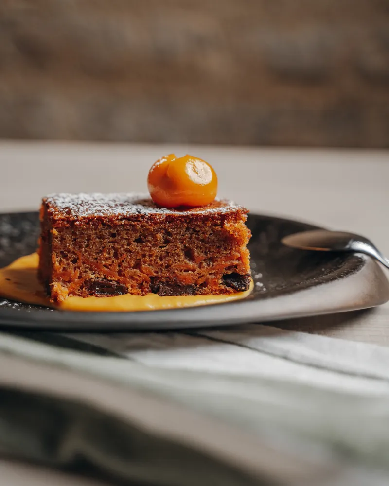A sponge cake topped with a kumquat, on pumpkin cream