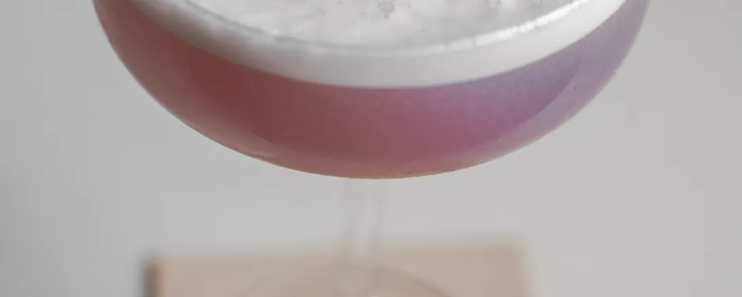 A pink cocktail with foam, up close
