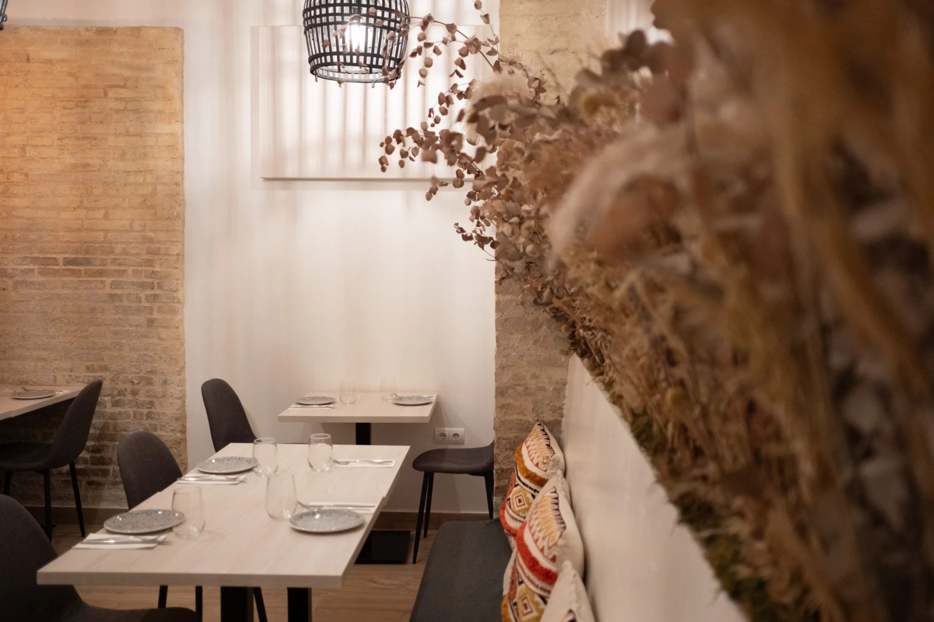 Mesas puestas junto a un banco y decoración de flores secas
