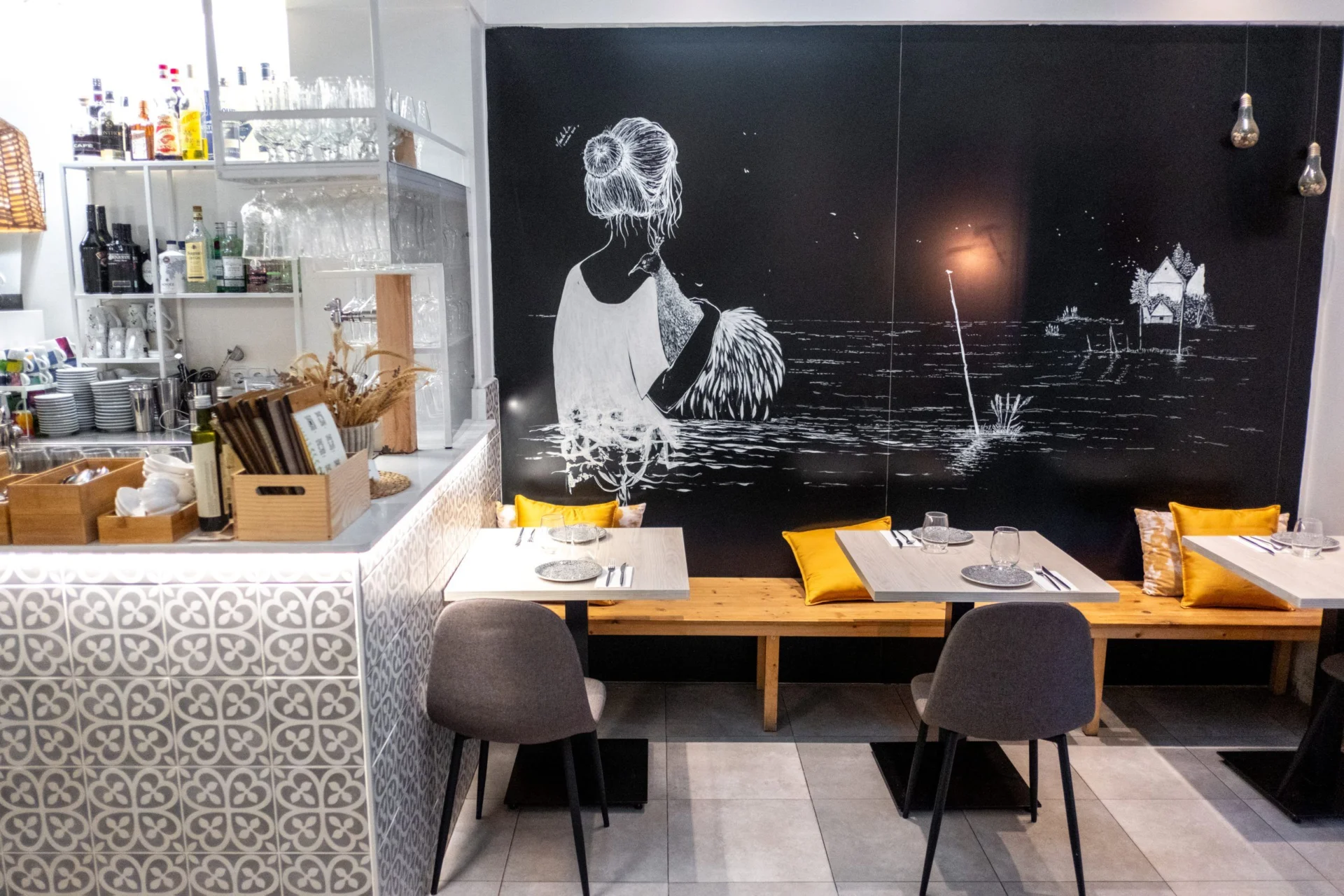 Interior con barra de azulejos estampados y mesas junto a un mural